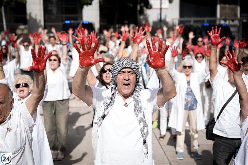 Médicos españoles rinden tributo a colegas en Gaza con batas blancas y manos rojas.